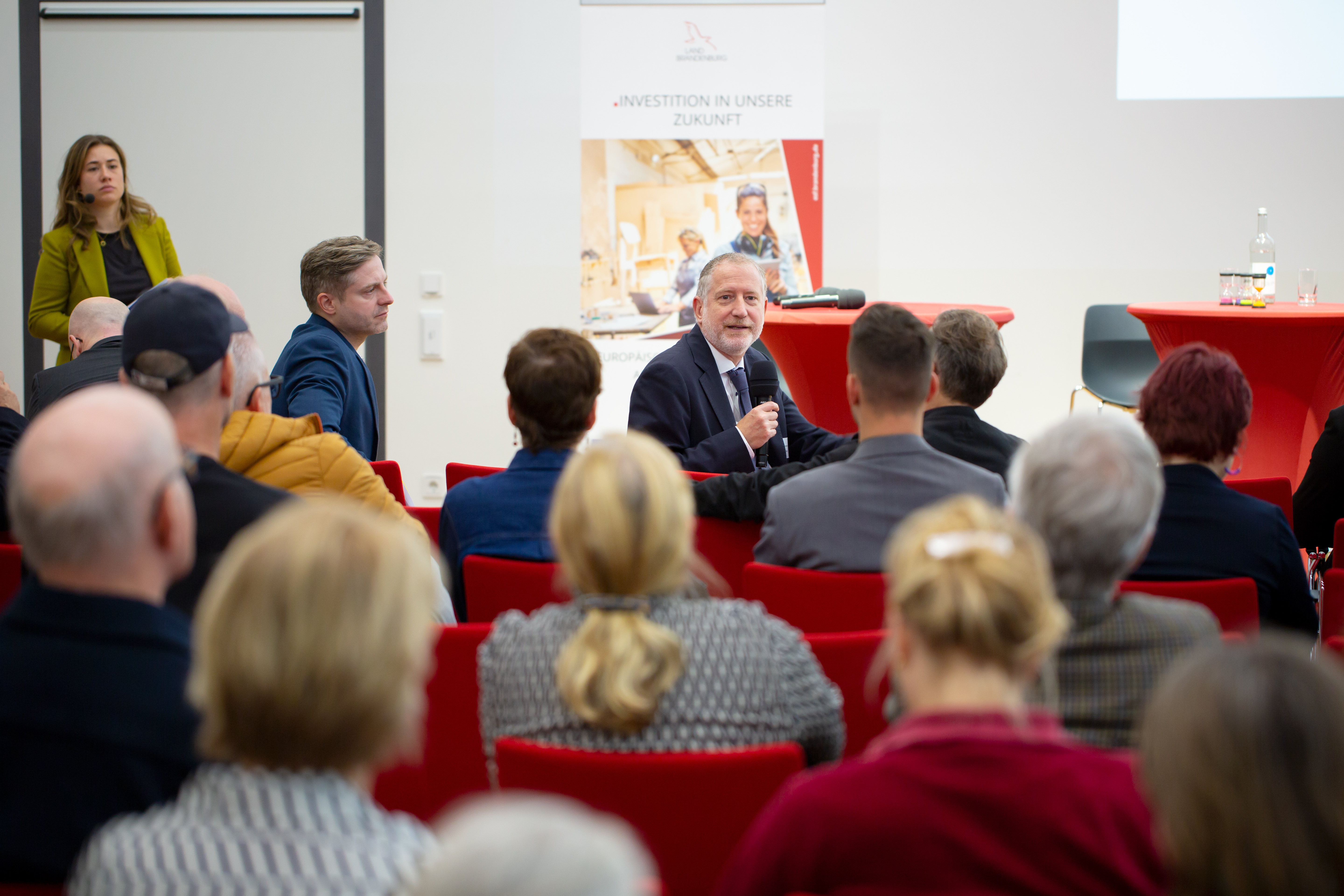 Bild: Patrick Paquet beugt sich auf seinem Stuhl in der ersten Reihe nach hinten, um eine Frage aus dem Publikum zu beantworten.