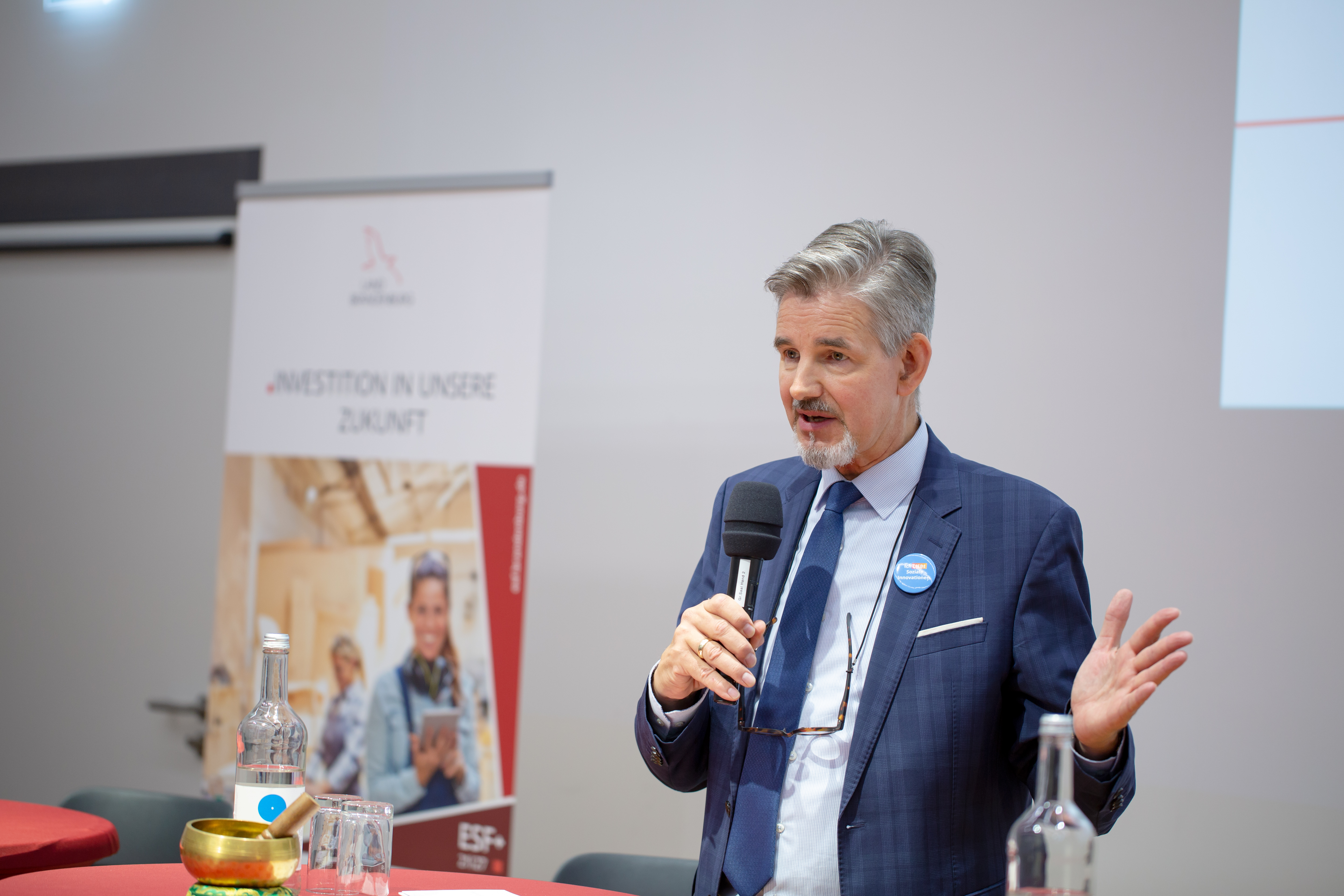 Bild: Dr. Steffen Kammradt, Geschäftsführer der Wirtschaftsförderung Land Brandenburg GmbH, an einem Stehtisch mit Mikrophon in der Hand.