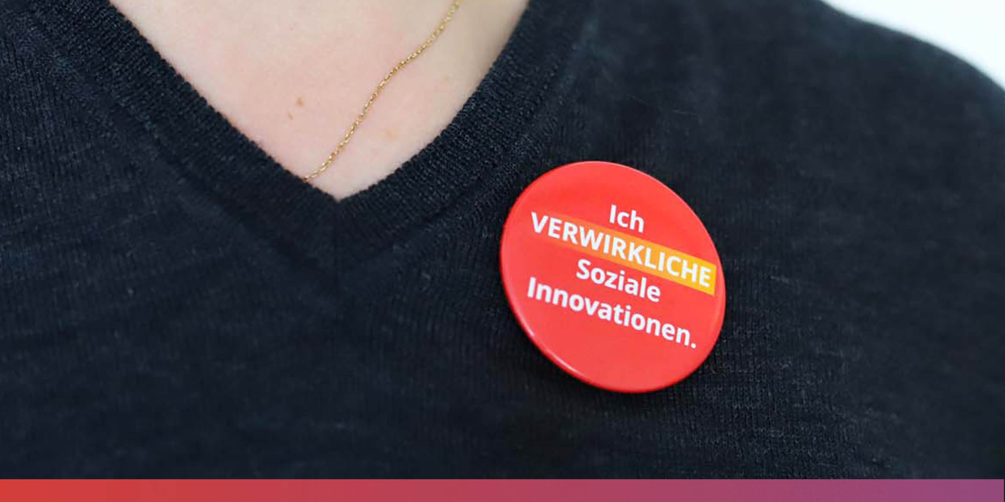 roter Button auf schwarzem Shirt mit der Aufschrift: 'Ich verwirkliche Soziale Innovationen'