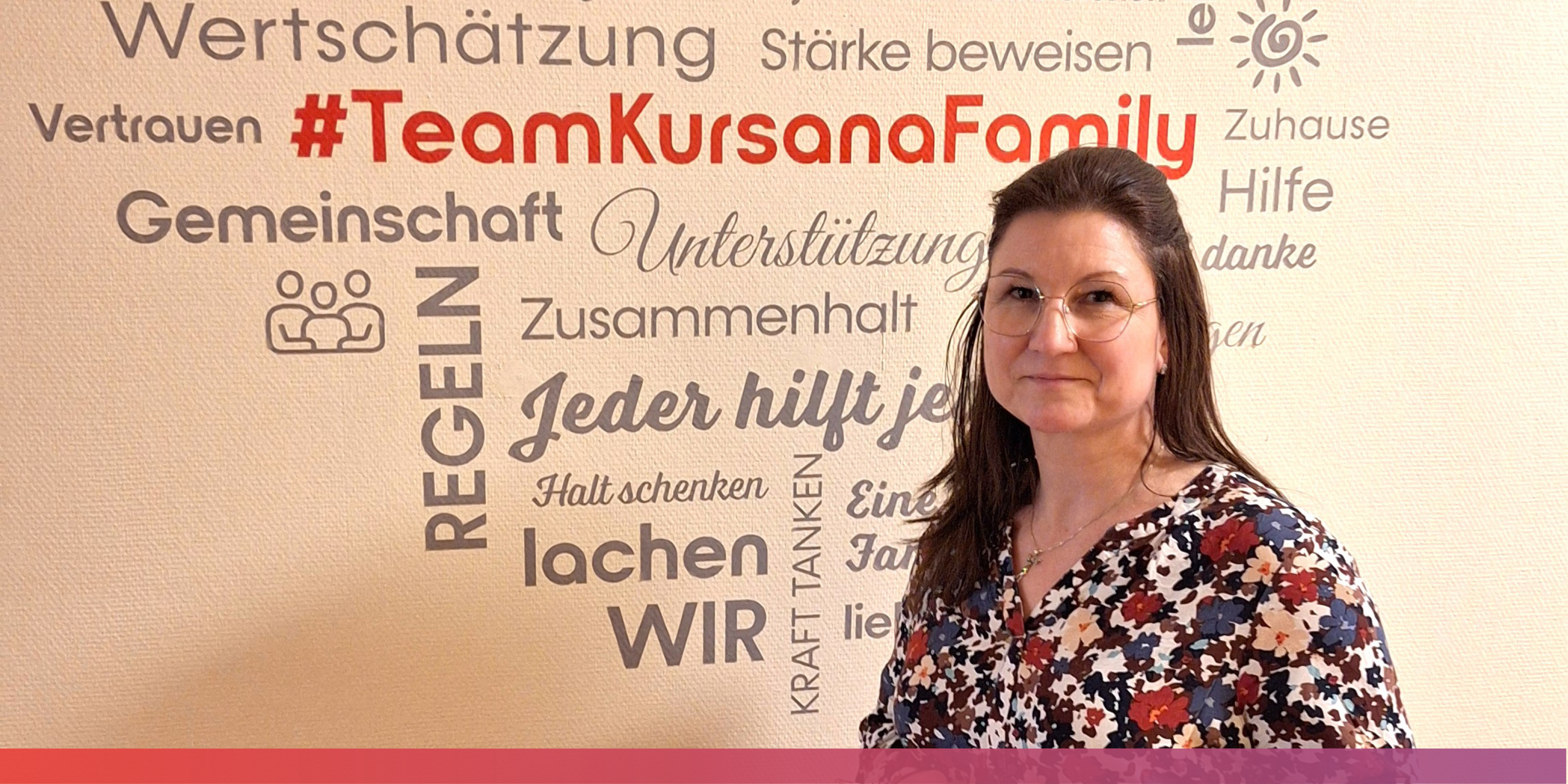 Eine Frau steht vor einer Wand an der viele Schlagworte stehen, die Zusammenhalt und Unterstützung konnotieren. In der Mitte steht #TeamKursanaFamily.