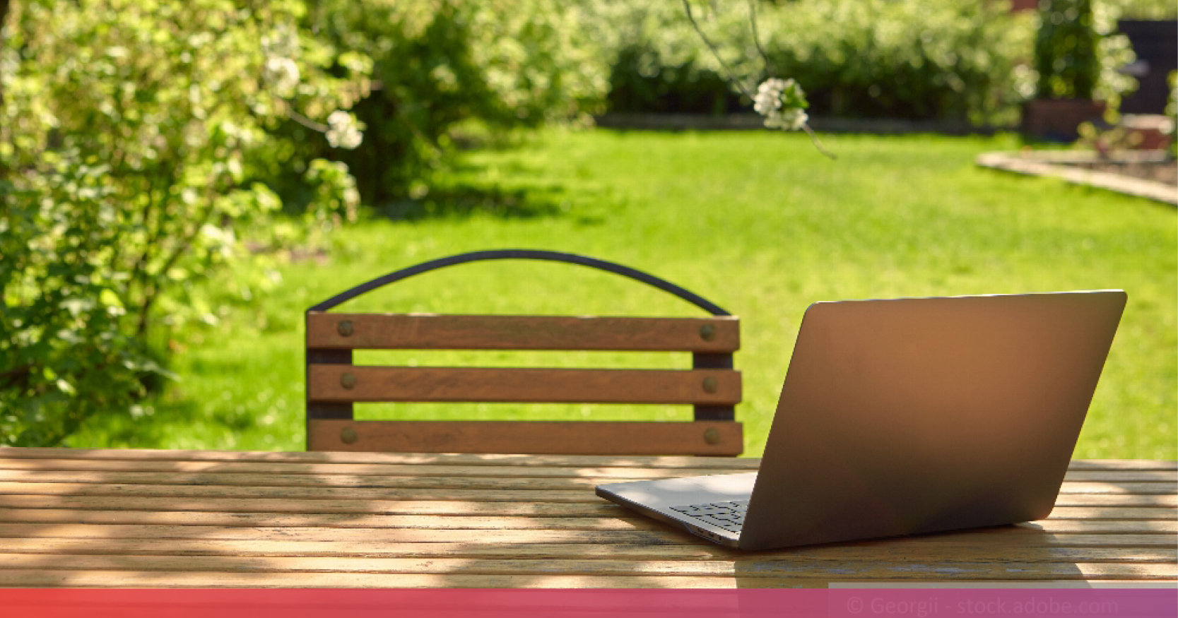 Ein Gartentisch auf dem ein aufgeklappter Laptop steht, im Hintergrund eine große Rasenfläche.